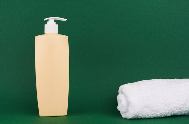 Bottle of shampoo or conditioner on color green background - Фото, зображення
