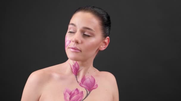Test Art: nő festett magnólia az arcán és bordák. Virág a testen. Portré fekete háttér - Felvétel, videó