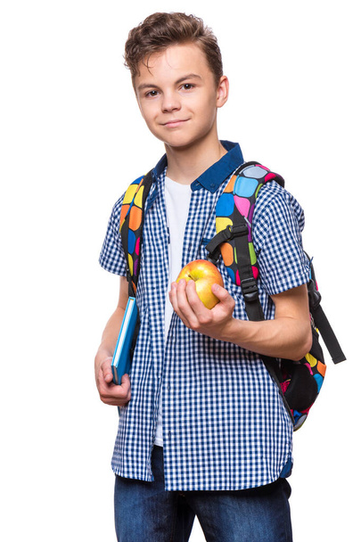 Portrait of young student with school bag, books and apple. Teenager smiling and looking at camera. Happy teen boy, isolated on white background. - Photo, Image