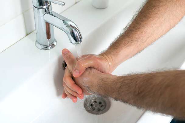 Az ember kezet mos szappannal és habszivaccsal. Védelem a koronavírus ellen. Coronavirus világjárvány elleni védelem gyakori kézmosással. Higiénia a coronavirus terjedésének megállítására. - Fotó, kép