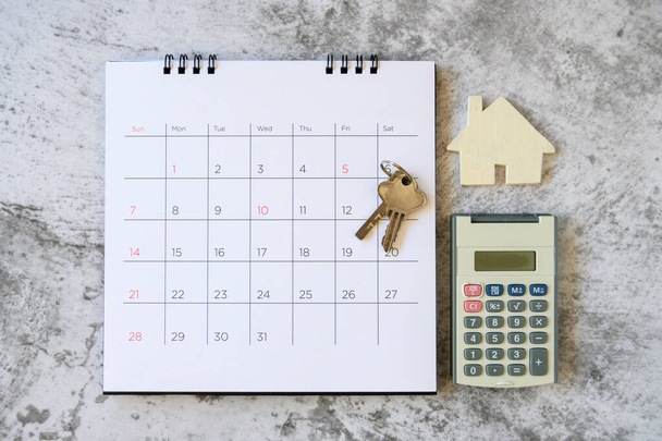 Ημερολόγιο και σπίτι στο τραπέζι. Ημέρα αγοράς ή πώλησης σπιτιού ή πληρωμή ενοικίου ή δανείου.  - Φωτογραφία, εικόνα