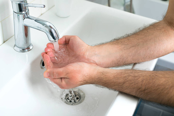 Ο άνθρωπος πλένει τα χέρια με σαπούνι και σαπουνάδες. Προστατέψτε από τον κορωναϊό. Coronavirus πανδημία προστασία με το πλύσιμο των χεριών συχνά. Υγιεινή για να σταματήσει η εξάπλωση του κορωναϊού. - Φωτογραφία, εικόνα