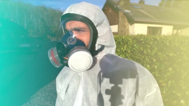 Homme portant un masque respiratoire complet et une combinaison blanche et des gants bleus pendant la pandémie et le confinement du virus du coronavirus covid-19 SRAS-CoV-2 dans le monde
. - Séquence, vidéo