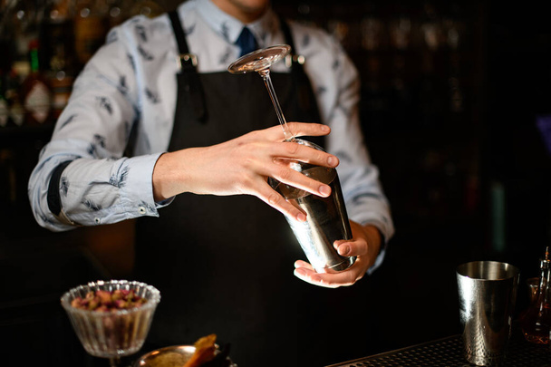 bartender holds in his hands steel shaker and empty glass - Foto, imagen
