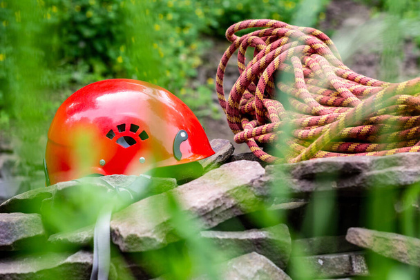 Zugangswerkzeuge zum Seil: Harter Hut, Seil, Karabiner. Bergsteigerausrüstung auf Felsen vor dem Hintergrund von Felsen und Grün - Foto, Bild