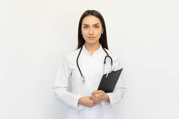 Friendly female doctor holding a folder in her hands, a stethoscope on her neck - Photo, Image