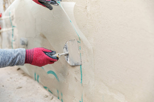 pracownik budowlany montujący siateczkę z włókna szklanego na ścianie - Zdjęcie, obraz