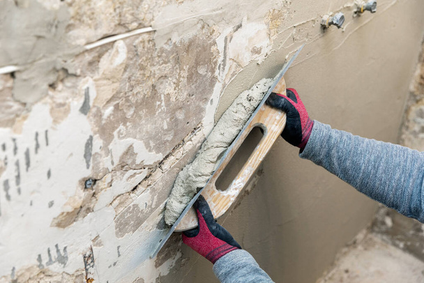 выравнивание стен - строитель, работающий с лопаткой и штукатуркой
 - Фото, изображение