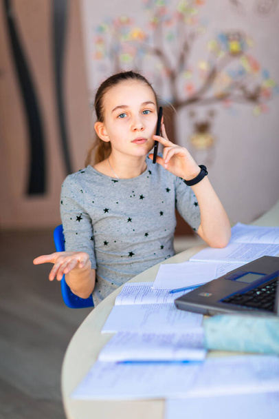 Beautiful young school girl working at home in her room with a laptop and class notes studying in a virtual class. Distance education and learning, e-learning, online learning concept during quarantine - Фото, зображення
