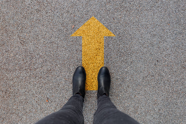 Musta kengät seisoo asfaltti betonilattia keltainen nuoli. Jalkojen kengät kävelevät ulkona. Nuorten selfie hipster
 - Valokuva, kuva