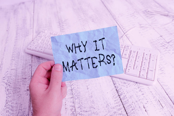 Word writing text Why It Matters Question. Business concept for most important thing to be done in a situation man holding colorful reminder square shaped paper white keyboard wood floor. - Photo, Image