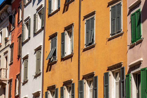 Fasada generycznych domów z licznymi oknami i okiennicami przy ulicy w Trentino Alto Adige, Włochy, Europa - Zdjęcie, obraz