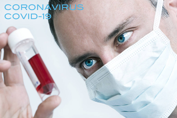 Male doctor wearing face mask with Coronavirus COVID-19 blood sample. Picture with text. - Foto, imagen