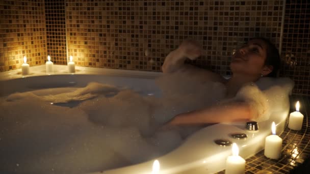 beautiful woman lies in a bubble bath by candlelight - Footage, Video