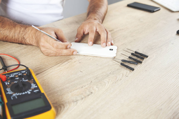 pracovník muž ruka rozbitý telefon na stole - Fotografie, Obrázek