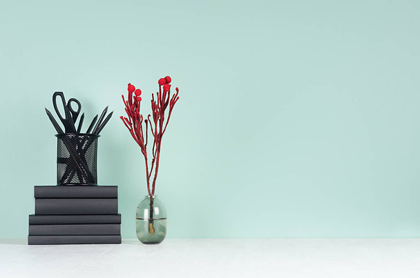 Fresh spring office workplace for business - black stationery, books, elegant decorative red branch in glass vase on green mint menthe wall and white wood table. - Foto, imagen