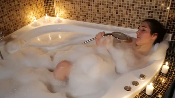 若い女性がキャンドルライトによって泡風呂で歌います - 映像、動画
