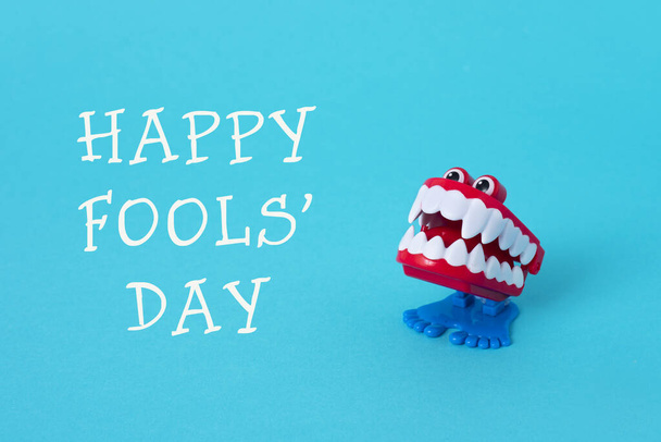 a funny denture and the text happy fools day on a bright blue background - Photo, Image