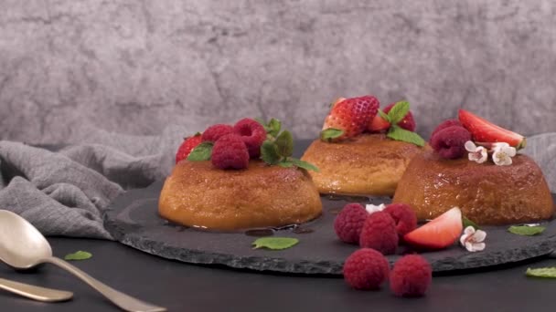 Caramel custard puddings on round slate on and dark kitchen countertop. - Video