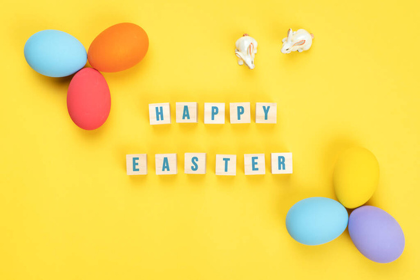 Paskalya günü sarı arka planda süslü yumurtaları olan küçük tavşancık. - Fotoğraf, Görsel
