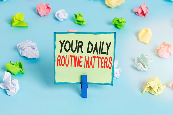 Conceptual hand writing showing Your Daily Routine Matters. Business photo showcasing practice of regularly doing things in fixed order Colored crumpled papers empty reminder blue floor clothespin. - Photo, Image