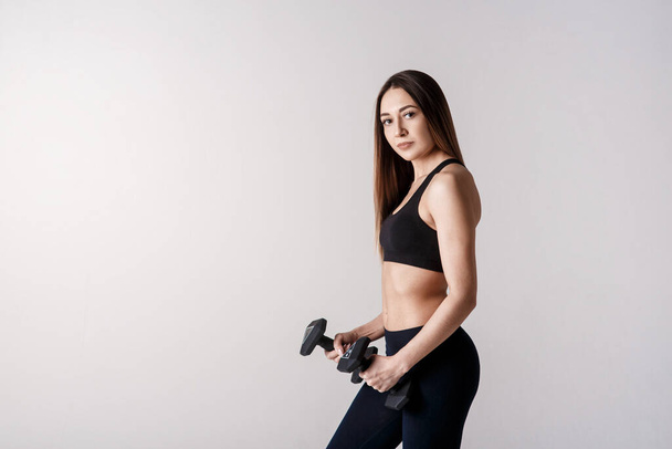 Strong muscular girl working out with dumbbells. Photo of attractive sporty girl isolated on white background. Strength and motivation. - Φωτογραφία, εικόνα
