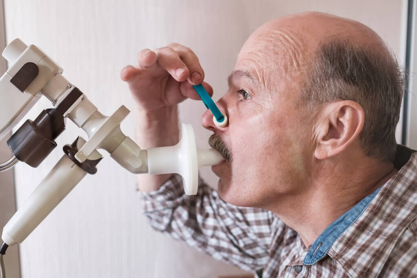 Idősebb spanyol férfi, aki spirometriával teszteli a légzést. Légzőszervi funkció diagnosztizálása tüdőbetegségben - Fotó, kép