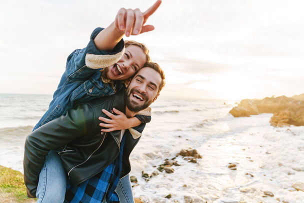 Зображення красивої молодої кавказької пари посміхається і скарбничка під час прогулянки на морі
 - Фото, зображення