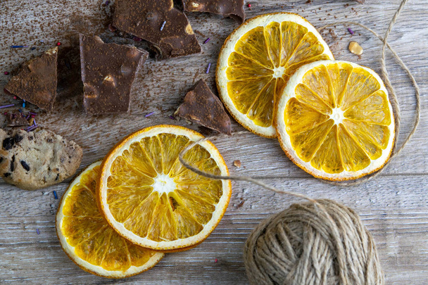 Dried oranges, chocolate slices, chocolate biscuits and cinnamon on a wooden table. - Photo, Image