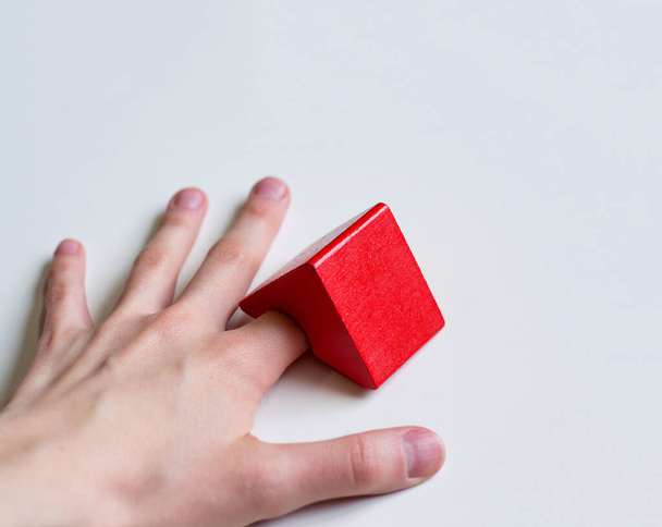 foto mão em um fundo branco com um dedo sob o telhado vermelho
 - Foto, Imagem