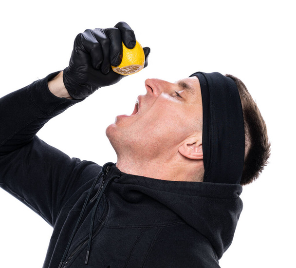 Zwiększenie odporności i opieki zdrowotnej. mężczyzna wyciskając połowę cytryny do ust na białym tle - Zdjęcie, obraz