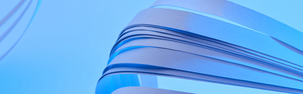 zblízka pohled na zakřivené barevné papírové pruhy na neonově modrém pozadí, panoramatický záběr - Fotografie, Obrázek