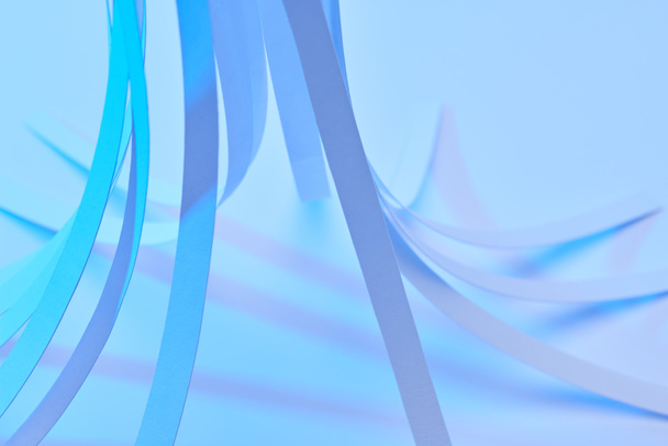close up view of curved paper stripes on neon blue background - Photo, Image