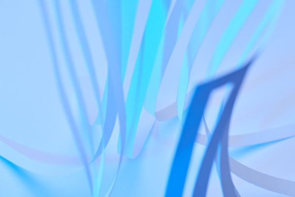close up view of paper stripes on neon blue background - Fotografie, Obrázek