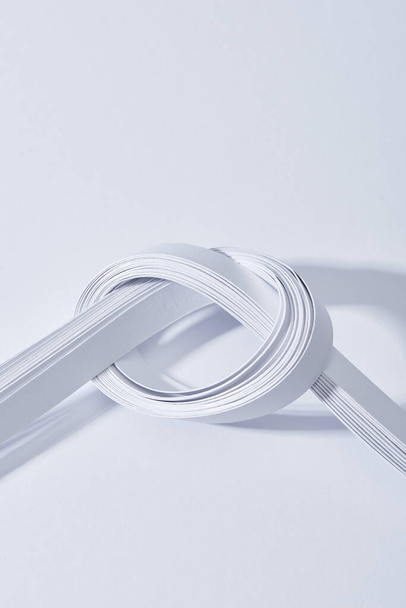 close up view of paper stripes in knot on white background - Fotoğraf, Görsel