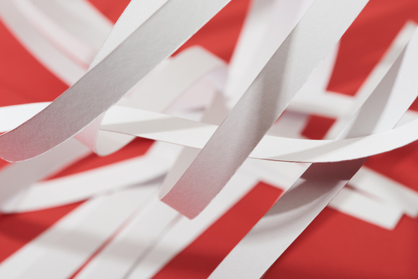 Kırmızı arkaplandaki beyaz kağıt şeritlerinin görünümünü kapat - Fotoğraf, Görsel