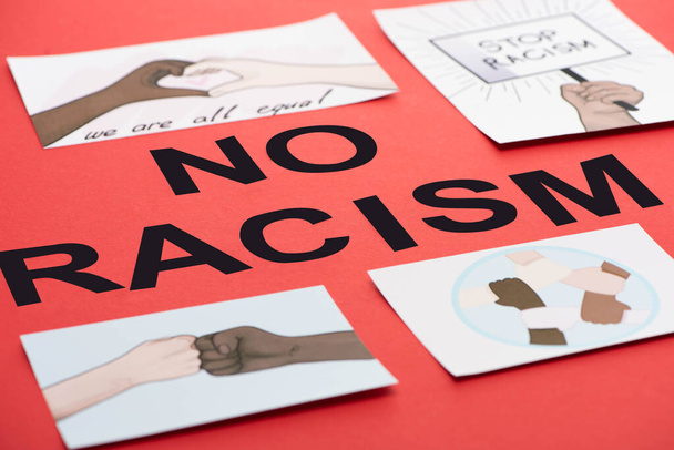 black no racism lettering among pictures with multiethnic hands on red background - Foto, afbeelding