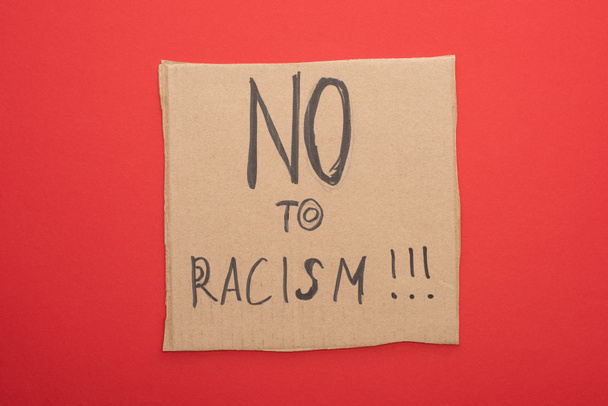 top view of carton placard with no to racism lettering on red background - Zdjęcie, obraz