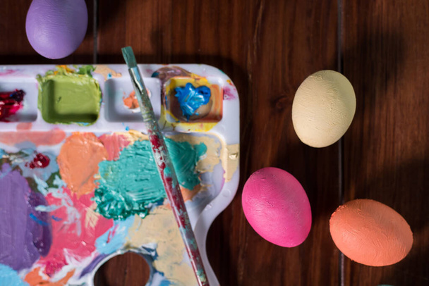 palette with paint brushes  and easter eggs - Фото, изображение