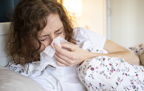 woman sneezing or coughing in bed coronavirus symptoms - Photo, Image