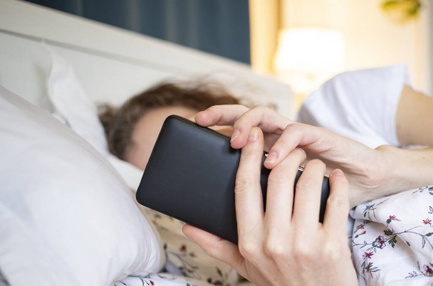 Nainen käyttää älypuhelinta sängyssä - Valokuva, kuva