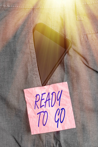 Text sign showing Ready To Go. Conceptual photo prepared and suitable to move or to travel to another place Smartphone device inside formal work trousers front pocket near note paper. - Photo, Image