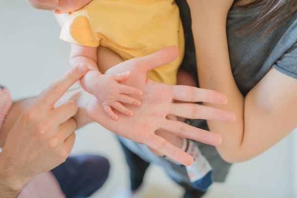 Close shot of a mother and father holding their newborn baby and showing the baby's hand over the father's hand. Motherhood and fatherhood concept - Photo, image