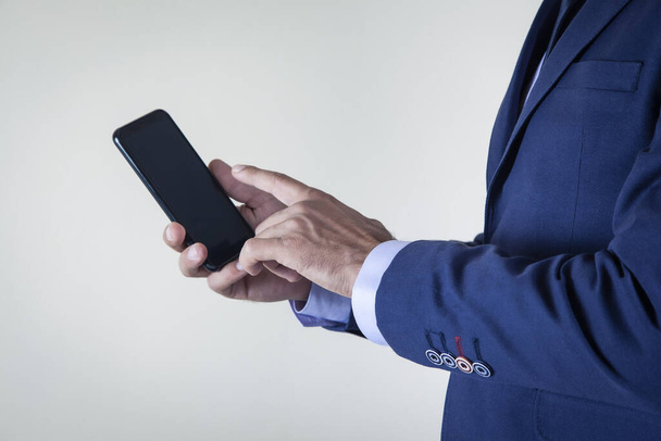 man hand houden smart phone op grijze achtergrond - Foto, afbeelding