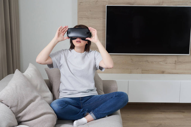 Šťastná mladá žena hraje na VR brýle uvnitř, Virtuální realita koncept s mladou dívkou baví s brýlemi sluchátka, s kopírovacím prostorem - Fotografie, Obrázek