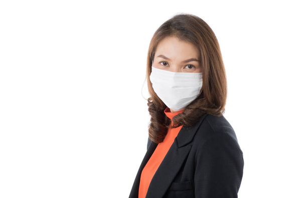 Schöne Asiatin in lässiger Businesskleidung mit chirurgischer Hygiene Schutzmaske auf weißem Hintergrund und Blick in die Kamera. Idee zur Vorbeugung gegen Coronavirus-Ausbruch und sicher in verschmutzter Luft. - Foto, Bild