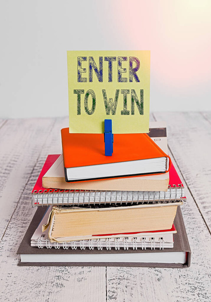 Text sign showing Enter To Win. Conceptual photo exchanging something value for prize or chance of winning pile stacked books notebook pin clothespin colored reminder white wooden. - Photo, Image