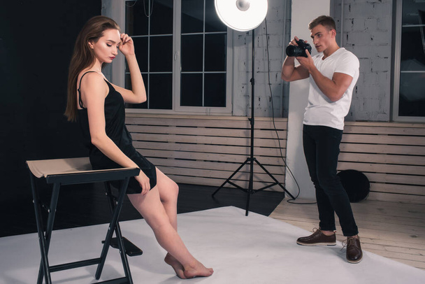 A guy photographer takes photos of a girl model in a Studio on a white background - Foto, imagen