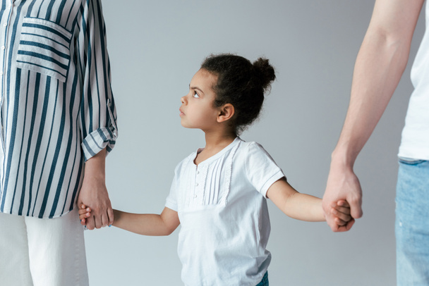 triste afroamericano chico cogido de la mano con divorciado adoptivo padres aislado en gris
   - Foto, imagen