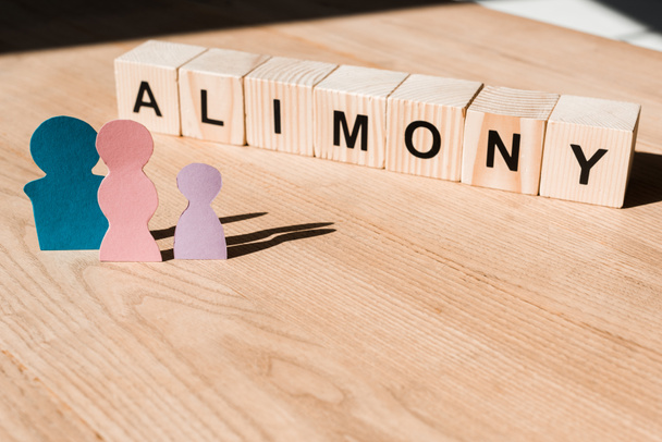 wooden blocks with alimony lettering near family paper people on textured surface  - Photo, Image